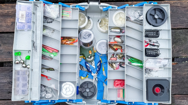 An open tackle box shows a variety of reels, hooks, and lines.
