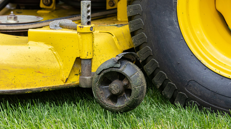 Close-up of a dirty and damaged mower deck gauge wheel