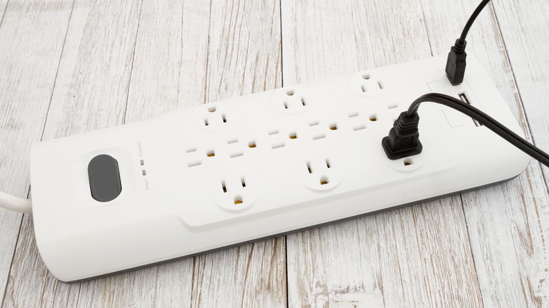 A white surge protector with two devices plugged in.