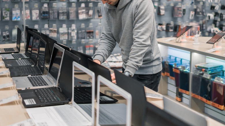 a person looking at refurbished laptops in a store