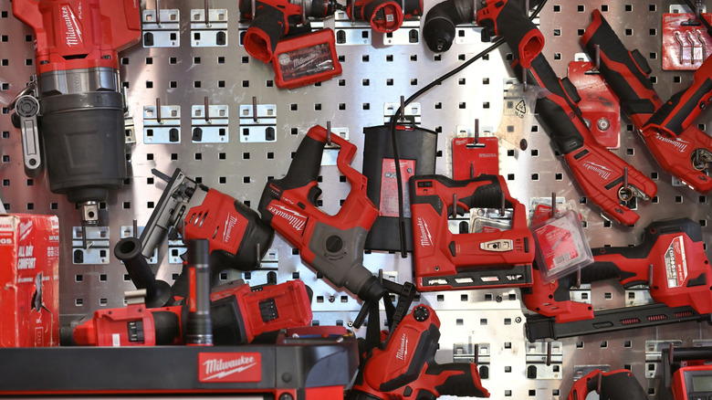 Several different Milwaukee power tools on display on a steel wall