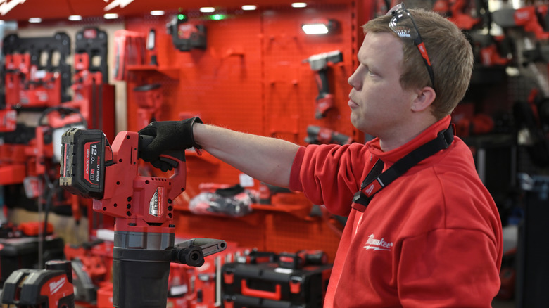 A person displaying and explaining Milwaukee power tools to off-screen customers