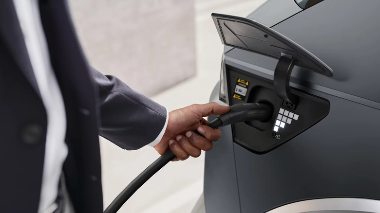 close-up of a person's hand plugging a charger into a gray 2027 Hyundai Ioniq 5