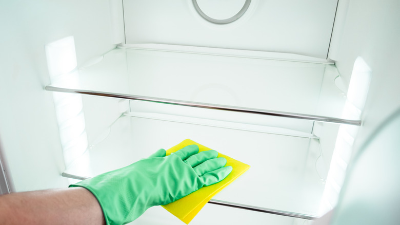 A person cleaning inside of a refrigerator