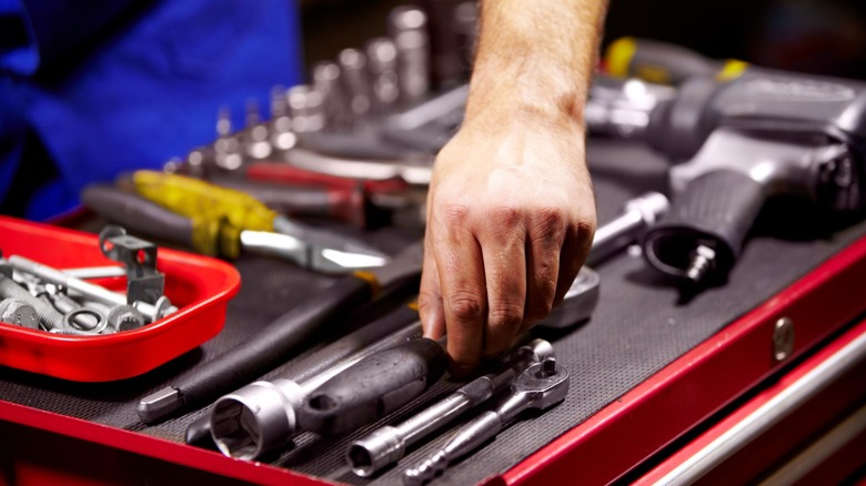A mechanic selects tools from a tool tray.