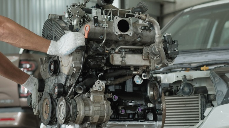 A mechanic removing an old engine from a car and preparing for a new engine