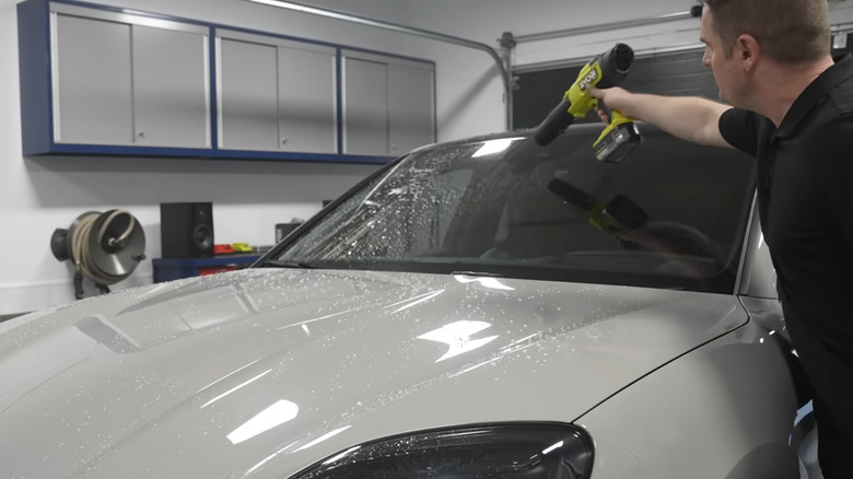 Man drying a Porsche with a car blow dryer