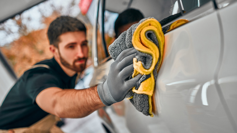 Man using towel to dry car