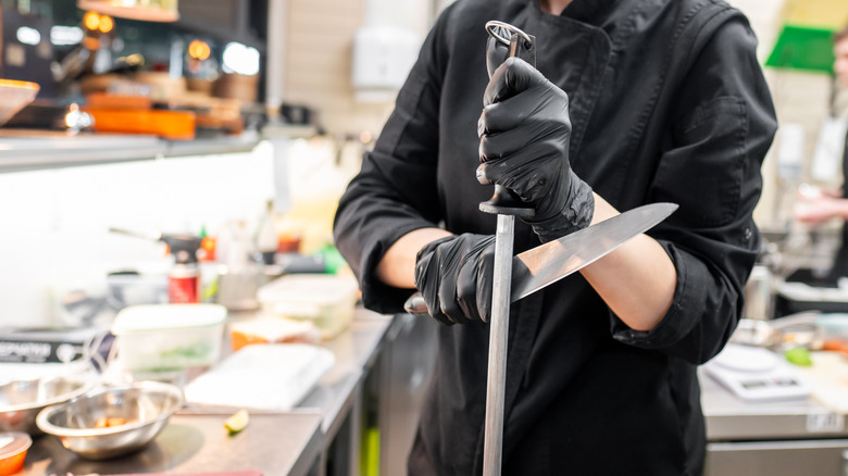 Chef sharpening a kitchen knife with Honing steel