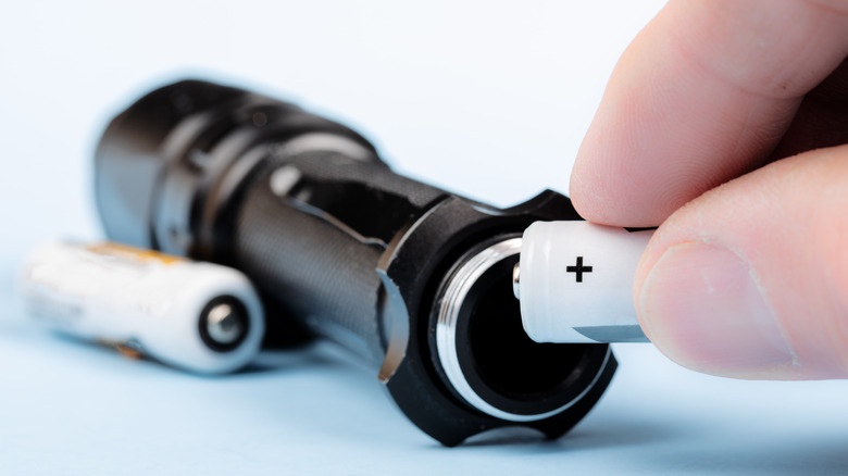 Inserting alkaline batteries into a flashlight