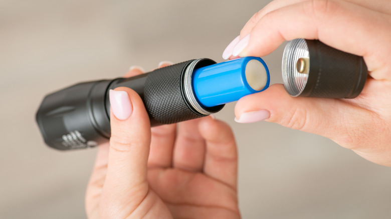 A shot of someone taking batteries out of a flashlight