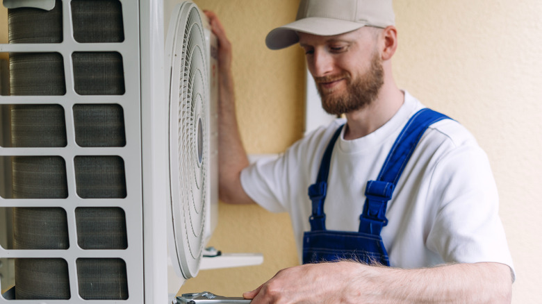 Man performing maintenance on outdoor air conditioner unit.