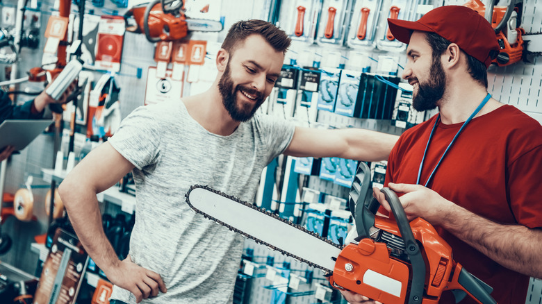 Shopper discussing chainsaw with sales professional.