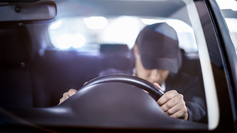 person sleeping behind steering wheel