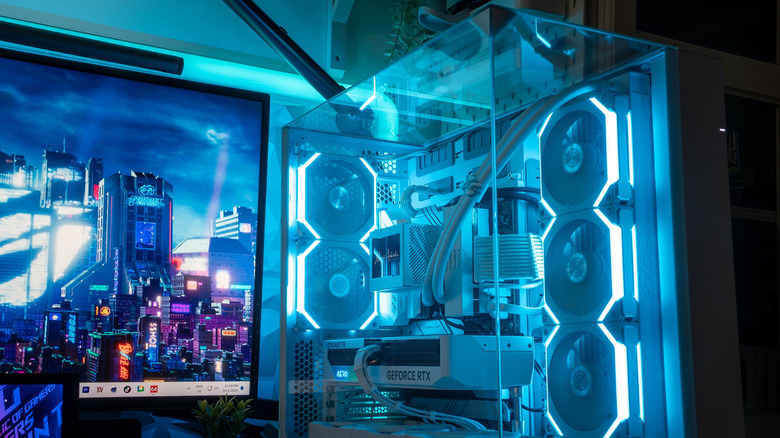 A monitor and a gaming PC, showing an AIO cooler inside