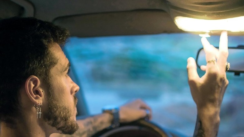 Man turns on ceiling light from driver's seat of car