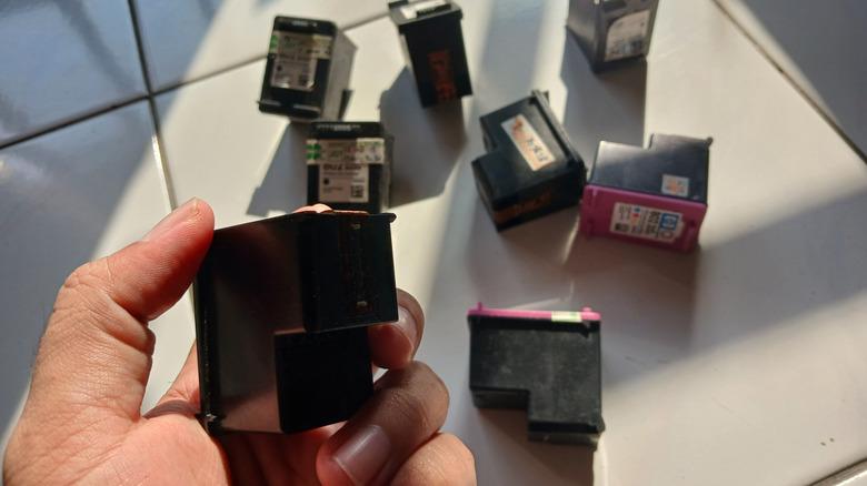 Hand holding a used ink printer cartridge.