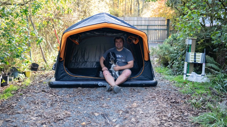 Andy Zahn and a dog sitting in the Portal Nomis One on a gravel driveway.