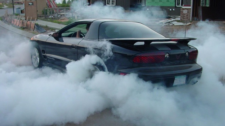 Black Pontiac Trans-Am doing a burnout on street