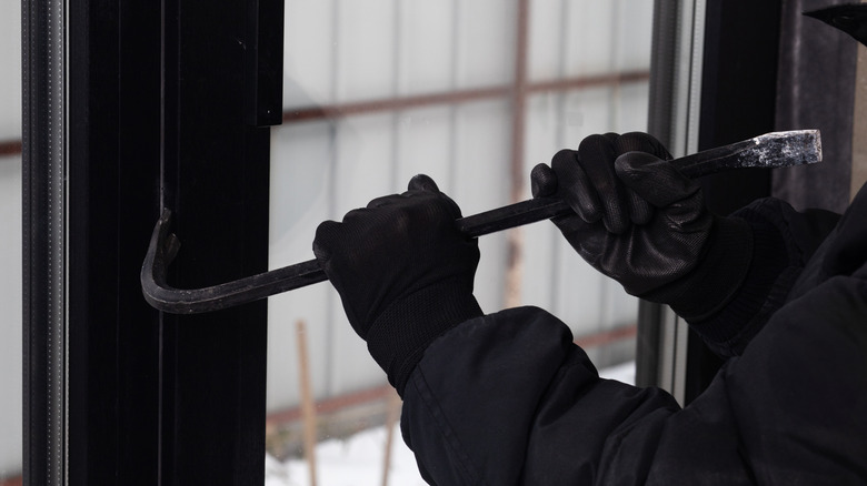 A person using a crowbar to break into a house