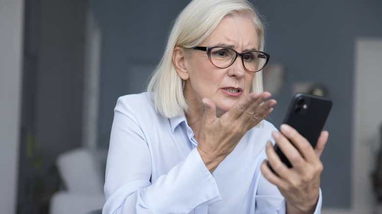 A woman making frustrated gestures at her smartphone