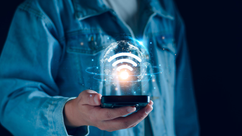 A person holding a phone with the WiFi symbol hovering above it showcasing connectivity