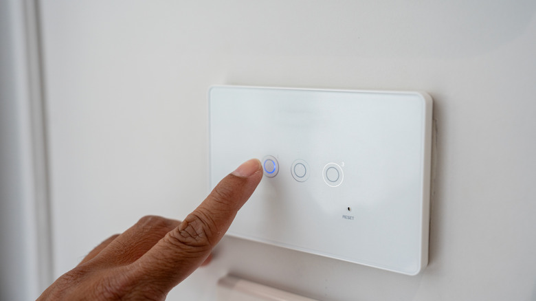 Person pressing smart light switch panel