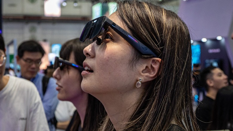 an attendee at Computex 2026 checking out the ROG XREAL R1 Edition 20 Gaming AR glasses paired with the the ROG XBOX Ally X20