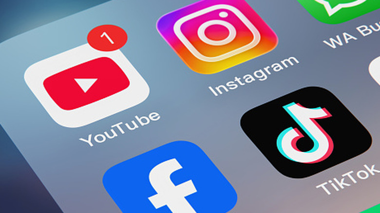 Multiple social media app logos on a phone screen.