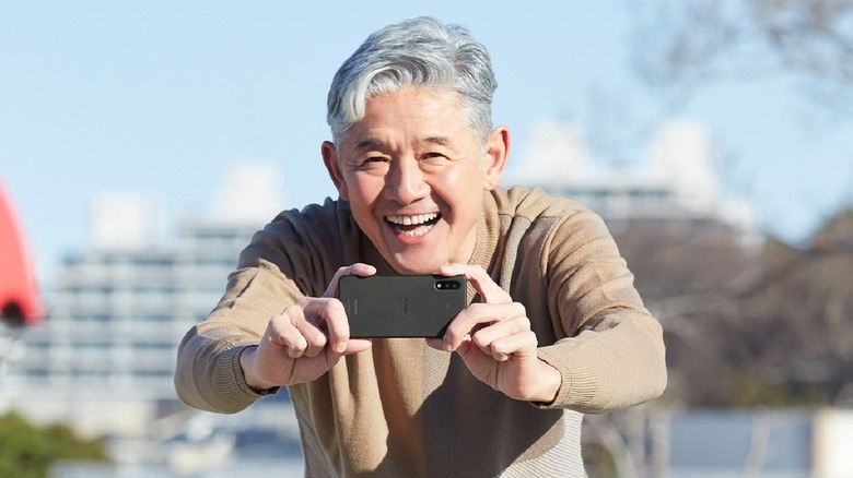 An old man smiling and holding the Sony Xperia Ace 2