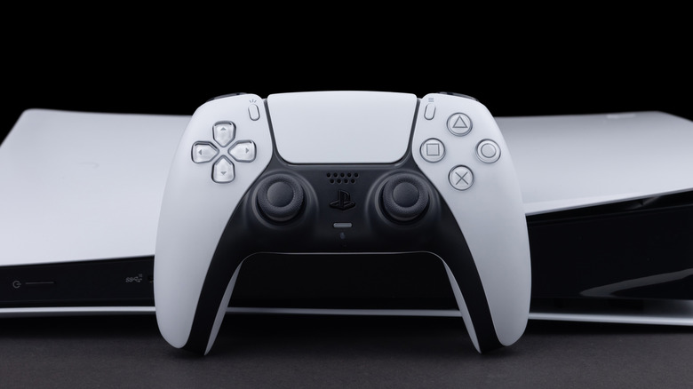 A PS5 controller leaning against a PS5 console.
