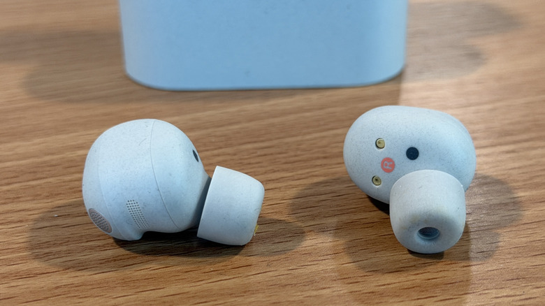 White Sony WH-1000XM6 wireless earbuds on a wood table