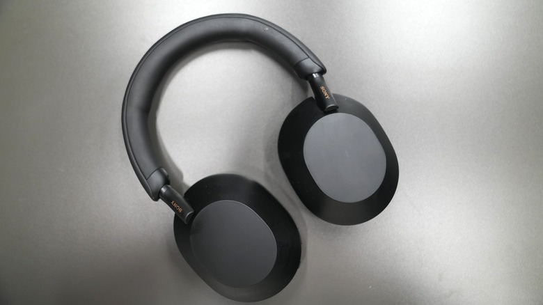 A pair of black Sony WH-1000XM5 headphones lying, face-down on a gray table, with the Sony logo visible.