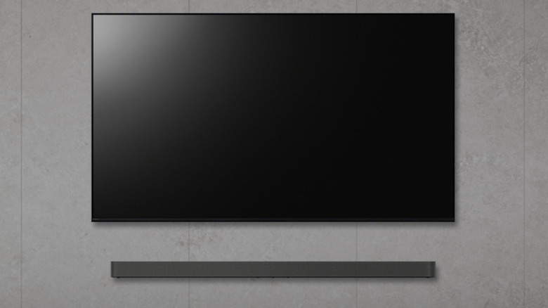 TV on the wall, a soundbar under it, and two speakes placed on both sides.