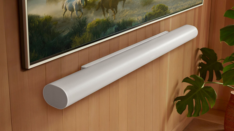 A white soundbar mounted on a wooden wall under the TV.