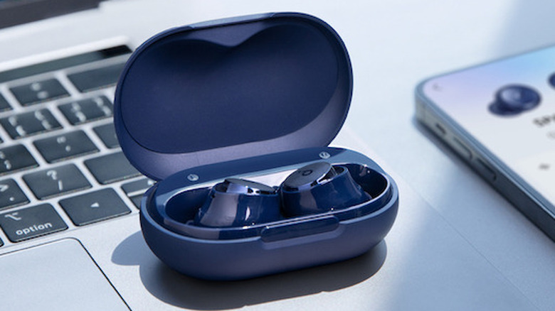 Soundcore Space A40 earbuds in blue sitting in the case, showcasing a work scene with a laptop and phone.