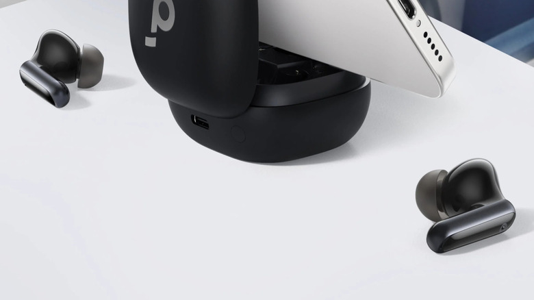The Soundcore P40i earbuds case being used as phone holder with one earbud next to it on the table.