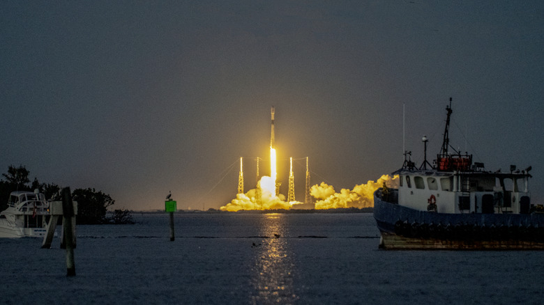 A SpaceX Falcon 9 rocket launches from Florida, with this image showing the rocket clearing the lightning arrestor towers at dusk.