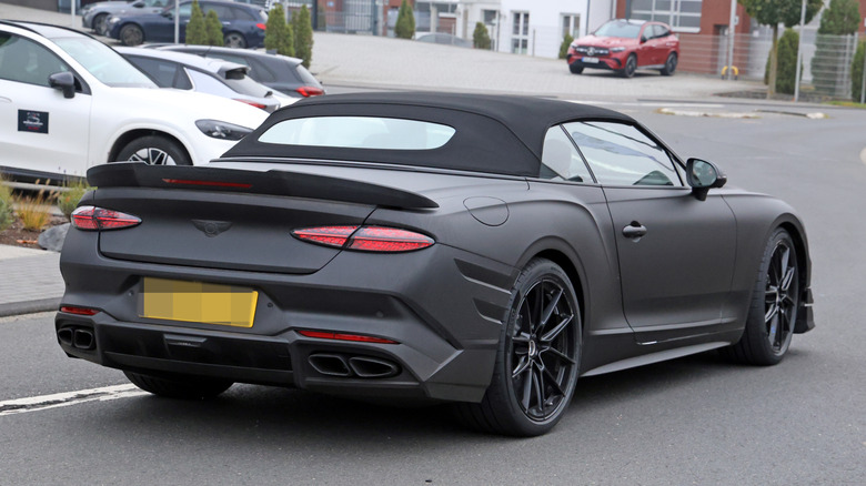 A rear three-quarter view of an alleged matte black Bentley Continental Supersports convertible driving on the road.