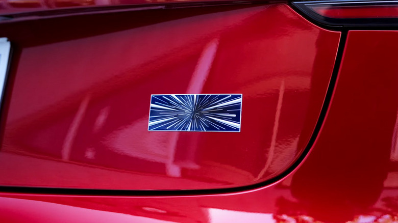 A red 2024 Tesla Model 3 Performance with starburst trunk badge.