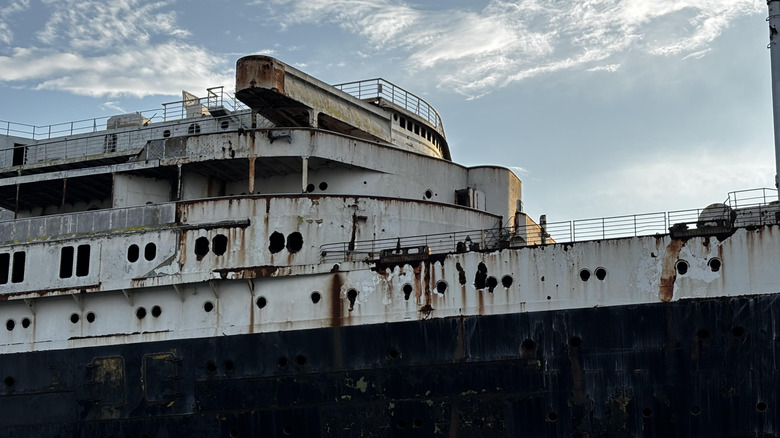 Side of SS United States ocean liner showing rust and removed windows.