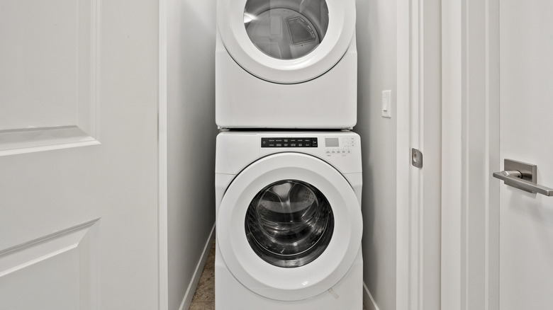 A washer and dryer stacked in a small, white space