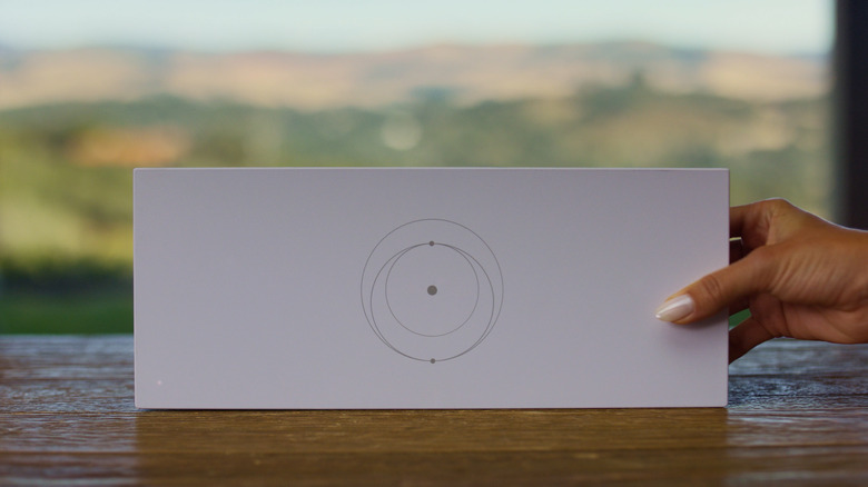 A person holding Starlink Gen 3 Router and placing it on table