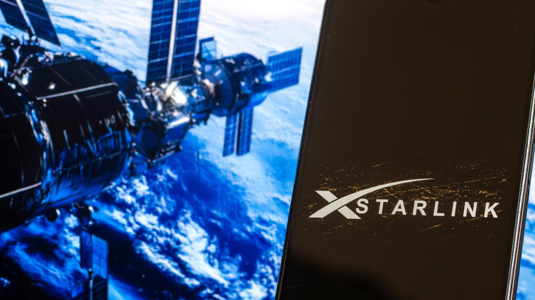 STARLINK logo displayed on a smartphone near satellite in outer space