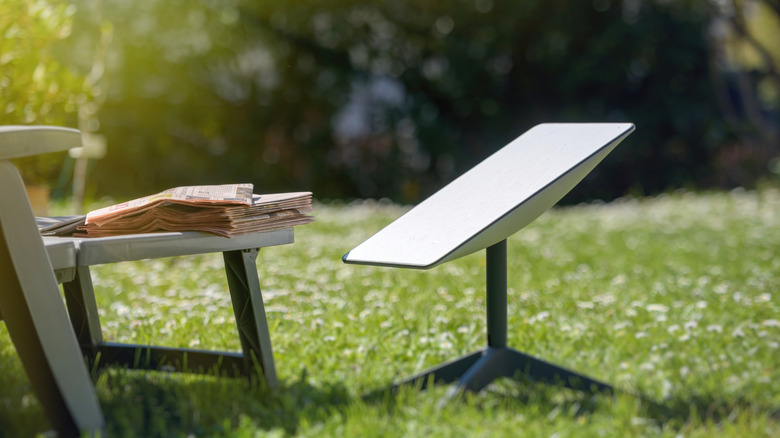 Starlink dish in a garden next to a lawn chair