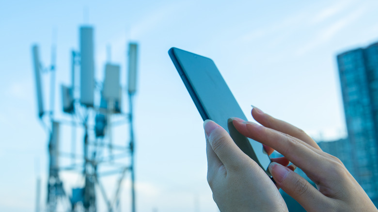 person using smartphone with celltower