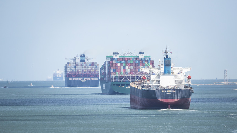 Stern-on view of a line of cargo vessels departing a port.