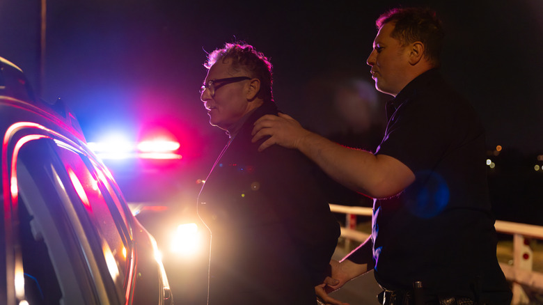 A police officer arresting a driver at night