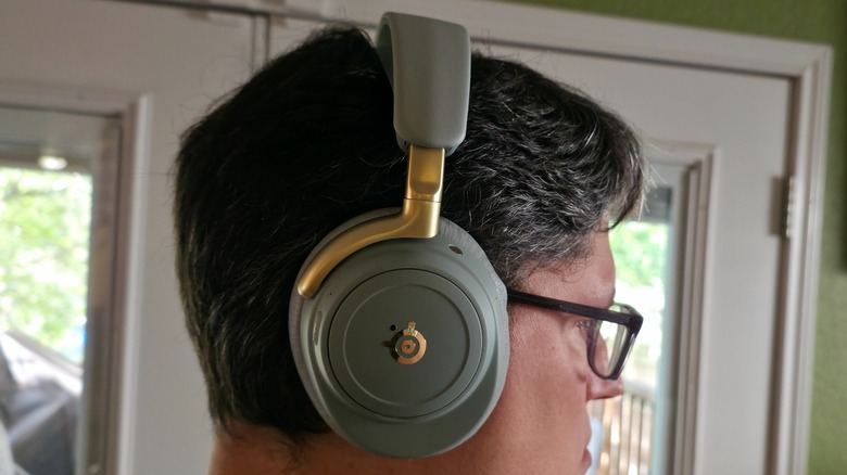 A man with glasses wearing a pair of Arctis Nova Elite gaming headphones