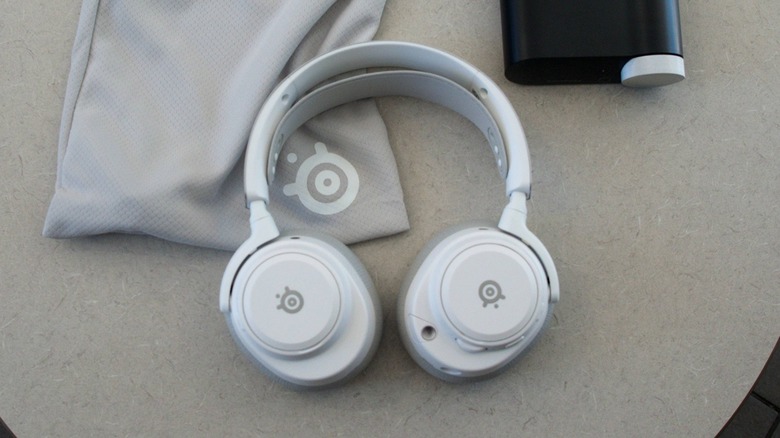 SteelSeries Arctis Nova Pro Omni gaming headset on a table with bag and controller
